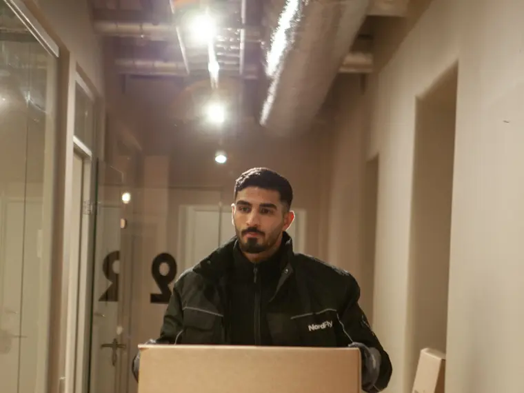 Nordflytt medarbetare bär flyttlåda genom korridor